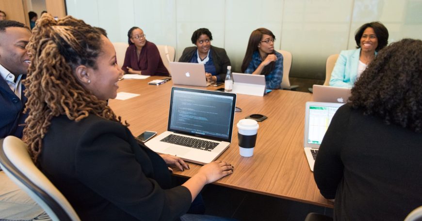Business team reviewing cyber insurance requirements together on laptops in a conference room